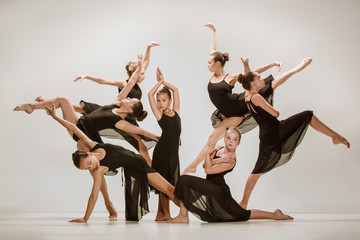 Naklejka premium The group of modern ballet dancers dancing on gray studio background