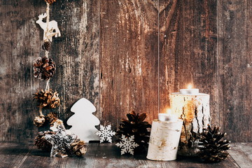 Christmas cozy composition. Xmas decorations on dark vintage wooden background, candle, wooden decor, ornaments, garland. Home interior, Christmas decor. New Year, winter. copy space 