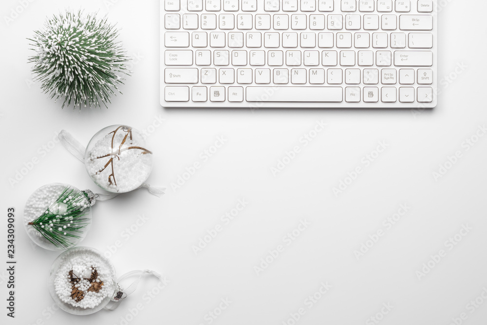 Poster flat lay office desk table with computer wireless keyboard,, mini christmas tree and christmas balls