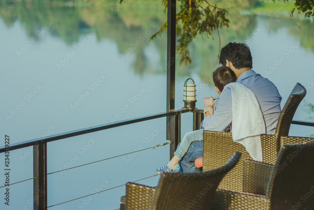 Wall mural Dad and son  waiting for mom on the waterfront balcony in the mo