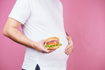 fast food and weight gain, gluttony, hunger, unhealthy eating. fat obese man with big tasty hamburger.