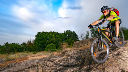 Fototapeta na wymiar Cyclist Riding the Bike on Rocky Trail at Sunset. Extreme Sport and Enduro Biking Concept.