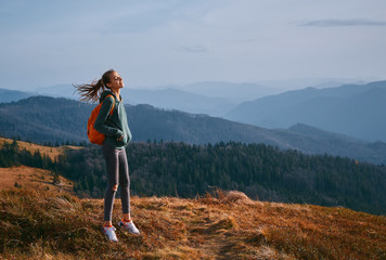 young woman standing on mountain ridge and enjoy the view at sunset