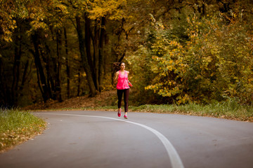 Fototapeta premium Young fitness woman running at forest trail