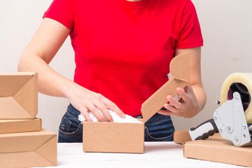 Woman packing cardboard boxes , picking and puttind products
