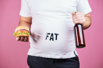 overeating, fast food, excess food, glutton, alcohol addiction, junk food. Fat obese man with...