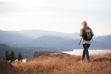 A young adult Caucasian woman hiking alone on a mountain peak, back view
