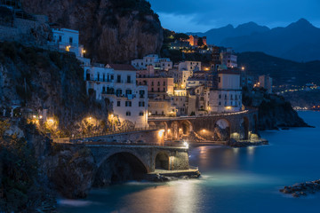 Fototapeta na wymiar Amalfi coast with street lights in the morning twilight and reflection on the sea. Italy. Long exposure