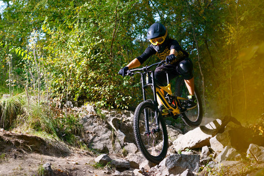 Professional Cyclist Riding the Mountain Bike on Autumn Forest Trail. Extreme Sport and Enduro Cycling Concept.