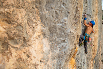Shirtless climber man climbing mountain wall on amazing sunny day 