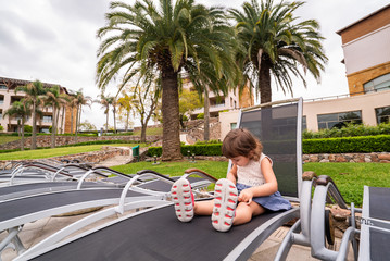 little girl with a tablet sitting on a lounger