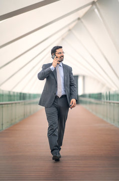 arab business man walking in a city and talking on a phone