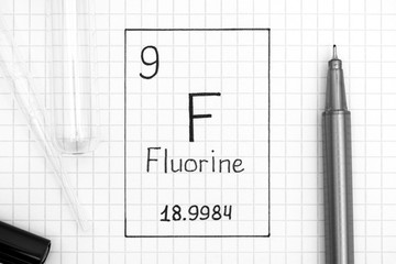 Handwriting chemical element Fluorine F with black pen, test tube and pipette.
