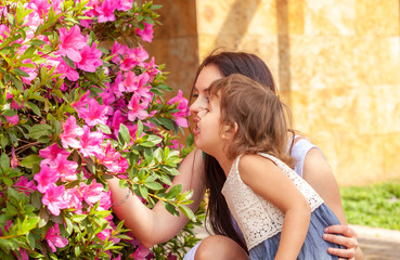 Naklejka premium daughter with mother near the bush of flowers