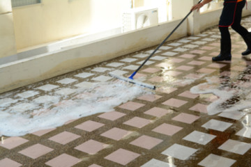 the  blurred of a woman with black boot cleaning  cement  floor with water and cleanser