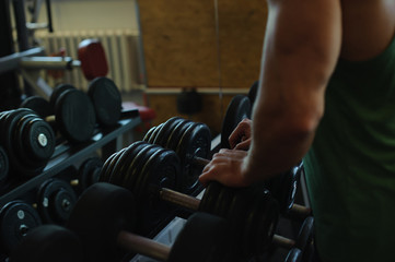 Young sexy male bodybuilder athlete, trains in the gym, using sports equipment and fitness equipment to improving health and beauty of the body