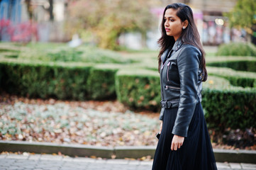 Pretty indian girl in black saree dress and leather jacket posed outdoor at autumn street.