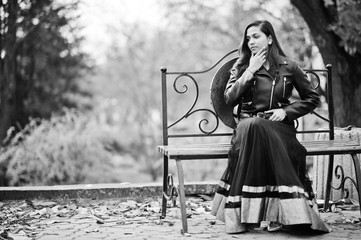 Pretty indian girl in black saree dress and leather jacket posed outdoor at autumn street and...