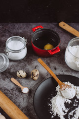 Ingredients and utensils for baking. Spoon with flour, dishes, eggs,  butter salt and rolling pin on a grey background. Flat lay. 