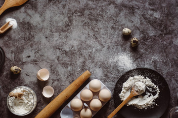 Ingredients and utensils for baking. Spoon with flour, dishes, eggs,  butter salt and rolling pin on a grey background. Flat lay. Text space