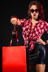 Black friday sale concept. Woman holding bags isolated on dark background. Handcuffed girl strapped...