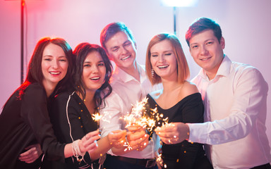 New year party, celebration and holidays concept - group of friends having fun with sparklers