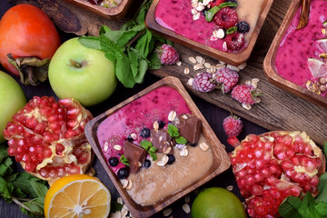 Smoothie bowl of two colours topped with chocolate pieces, bilberries, oatmeal flakes, mint and bran