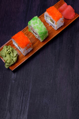 Fresh sushi rolls with cream cheese, rice, caviar and seafood against the black background. Asian cuisine meal