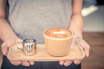 Close up barista serving coffee and syrup on wooden plate at coffee shop.