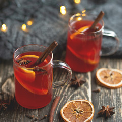 Christmas mulled red wine with spices and fruits on a wooden rustic table. Traditional hot drink in...