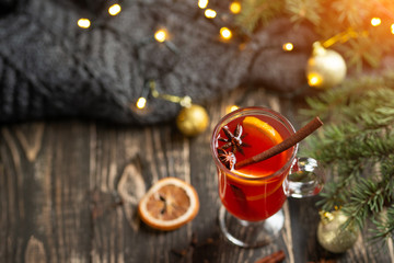 Christmas mulled red wine with spices and fruits on a wooden rustic table. Traditional hot drink in...