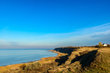 Fototapeta na wymiar Sea beach with small rocky lagoon and coastal grass. Deep blue sky. Russia Azov sea.