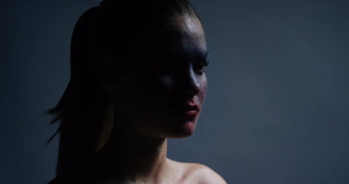 portrait beautiful woman wearing blue face paint makeup looking up exotic body art on attractive female performer creative expression light fading in dark background