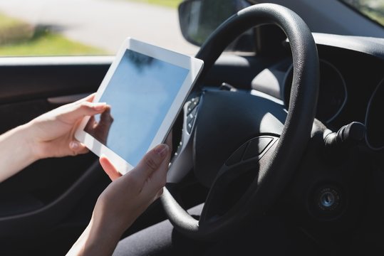 Woman using digital tablet in a car