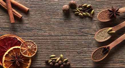 Cardamom, cinnamon sticks, cloves, nutmeg, anise stars, allspice, orange, grapefruit, lime.Different types of whole Indian spices in wooden background close-up. Healthy food.