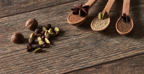 Cardamom, cloves, nutmeg, star anise, allspice. Different types of whole Indian spices in wooden background close-up. Healthy food.
