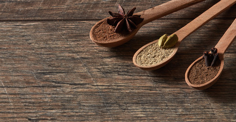 Cardamom, cloves, star anise. Ground spices in wooden spoons.Different types of whole Indian spices in wooden background close-up. Healthy food.