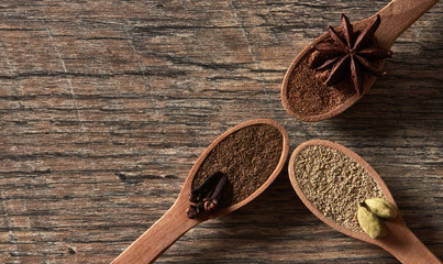 Cardamom, cloves, star anise. Ground spices in wooden spoons.Different types of whole Indian spices in wooden background close-up. Healthy food.