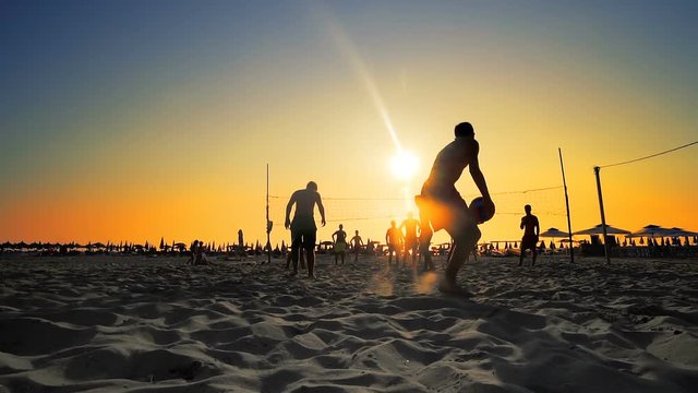 Beach volleyball silhouette during sport recreation at summer vacationat sunset, SLOW MOTION