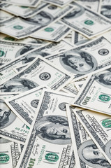 Background from dollars. Notes of one hundred American dollars are scattered across the background.