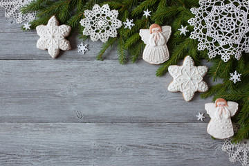 Christmas wooden background with fir branches, snowflakes and gingerbread angel