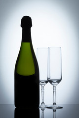 Botella de vino con copas de champaña a contraluz