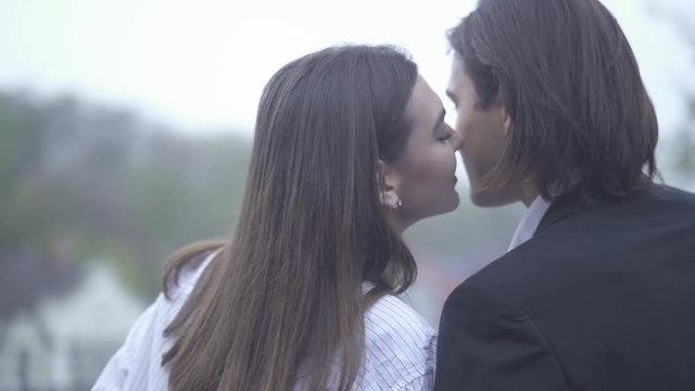 Beautiful girl kisses her boyfriend on the cheek outdoors Guy and girlfriend spending time together Couple in love Happy couple