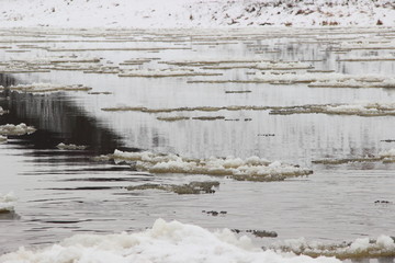 Winter day river European landscape - small ice floes floating on the water in spring