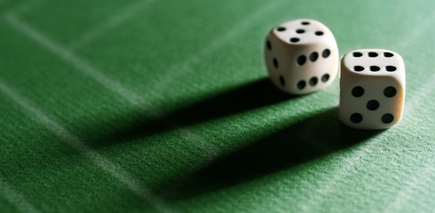 Dice game. Dice on the table. Illuminated with a contrasting light. Long shadows on the diagonal.