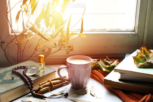  Autumn still life for muslim tradition m. cup of coffee,  orange scarf and maple leaves, holy book quran and rosary, siwak, oud perfume  on wooden background. the concept of cozy autumn.