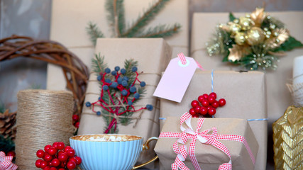 Label for the signature of a Christmas gift decorated with red and white ribbon among Christmas candles and lights next to cup of hot cocoa