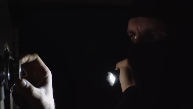 the thief is trying to open the safe in the night
