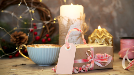 Label for the signature of a Christmas gift decorated with red and white ribbon among Christmas candles and lights