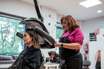 Woman in a professional hairdresser infrared hair dryer